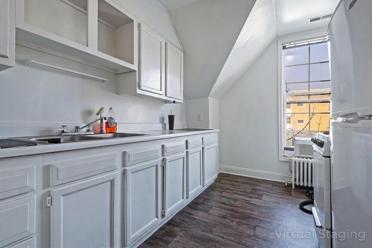 Kitchen featuring freestanding refrigerator, light countertops, dark wood-style flooring, vaulted ceiling, and white cabinets
