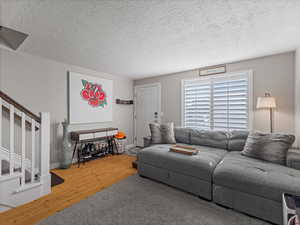 Living area with a textured ceiling, stairs, and wood finished floors