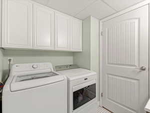 Washroom featuring washing machine and clothes dryer and cabinet space