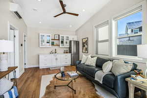 Living area featuring dark wood-type flooring, an AC wall unit, ceiling fan, and recessed lighting
