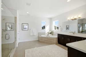Full bathroom featuring a stall shower, vanity, a bath, light tile patterned flooring, and recessed lighting
