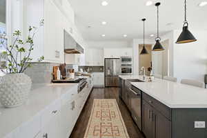 Kitchen featuring white cabinetry, pendant lighting, a breakfast bar area, light stone countertops, and recessed lighting