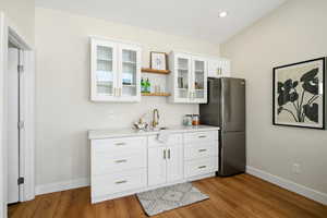 Kitchen featuring open shelves, glass insert cabinets, white cabinetry, freestanding refrigerator, and light stone counters
