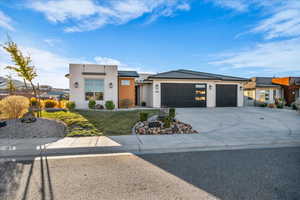 View of front facade featuring stucco siding, concrete driveway, a garage, and a front yard