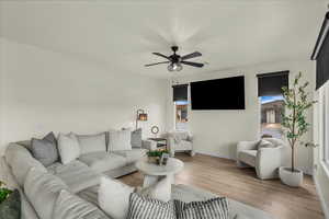 Living area with light wood-type flooring, a ceiling fan, and plenty of natural light