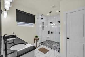 Bathroom with double vanity, a stall shower, recessed lighting, and light marble finish floors
