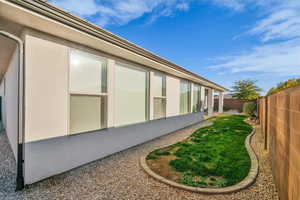 View of side of property with a fenced backyard and stucco siding