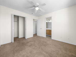 Unfurnished bedroom featuring carpet flooring, a closet, ceiling fan, attic access, and ensuite bathroom