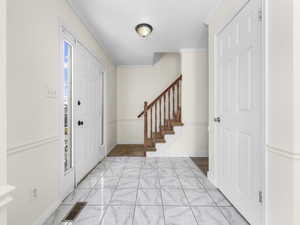 Entrance foyer with crown molding and stairs
