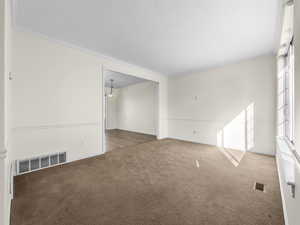 Carpeted spare room with crown molding