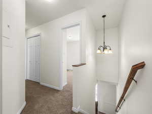 Hallway featuring an upstairs landing and carpet flooring