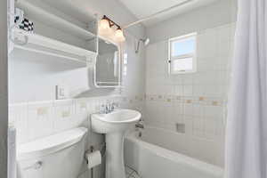 Full bath with shower / bath combo and tile walls