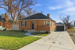 View of front facade featuring brick siding, driveway, a chimney, a shingled roof, and entry steps