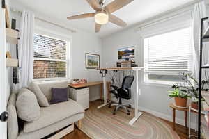 Office space featuring dark wood-style floors, ceiling fan, and plenty of natural light