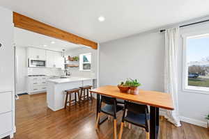 Dining area featuring dark wood finished floors, beam ceiling, and recessed lighting