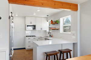 Kitchen featuring a breakfast bar, a peninsula, open shelves, white cabinetry, and dark wood finished floors