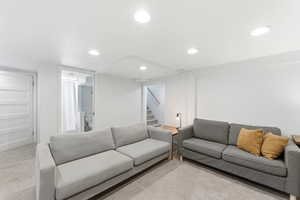 Carpeted living area featuring stairway and recessed lighting