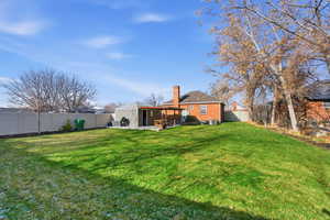 Rear view of property with a patio, a fenced backyard, a chimney, and brick siding