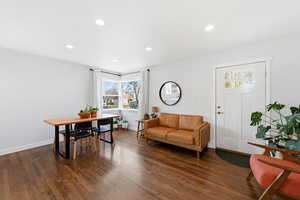 Living area with recessed lighting and dark wood-style flooring