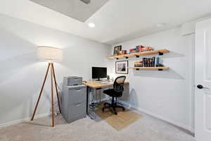 Office space with light colored carpet and recessed lighting