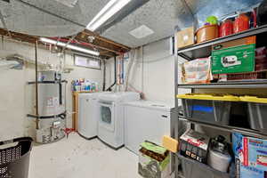 Laundry area featuring strapped water heater, concrete floors, and washing machine and dryer