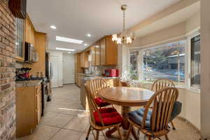 Dining room with skylights, light tile patterned flooring, a chandelier, and recessed lighting