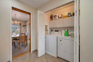 Laundry area with cabinet space, washing machine and clothes dryer, and light tile patterned floors