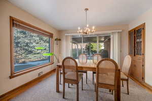 Dining room featuring a chandelier, baseboards and hardwood blinds