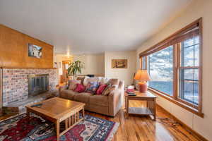 Living area with light wood finished floors, hardwood blinds and a wood burning fireplace