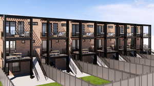 View of apartment building / complex featuring stairs and a fenced backyard