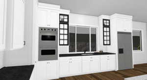 Kitchen featuring dark countertops, multiple ovens, white cabinets, built in fridge, and dark wood-style flooring