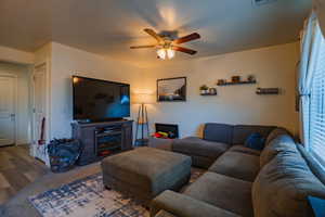 Carpeted living area with ceiling fan and a fireplace