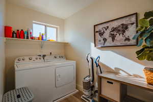 Washroom with washing machine and clothes dryer and wood finished floors