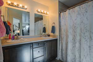 Full bath with double vanity and a shower with curtain