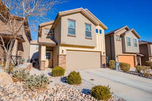 View of front of property featuring concrete driveway, a garage, stucco siding, stone siding, and board and batten siding