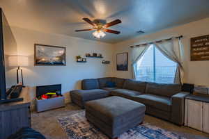 Living area featuring dark carpet and a ceiling fan