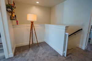 Hall with an upstairs landing, dark carpet, and recessed lighting