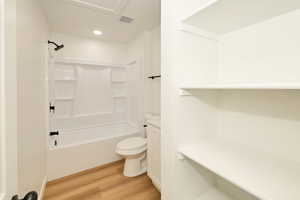 Full bathroom with washtub / shower combination, light wood-style flooring, and recessed lighting
