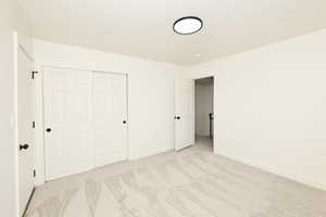 Unfurnished bedroom with a closet and light carpet