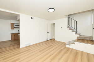 Unfurnished living room with light wood finished floors, stairs, and a textured ceiling