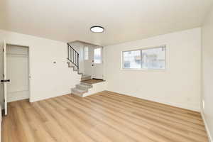 Unfurnished living room with light wood-style floors, stairs, and a textured ceiling