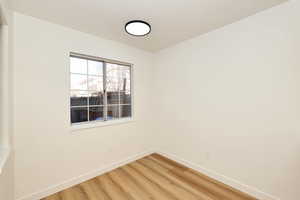Empty room with light wood finished floors and a textured ceiling