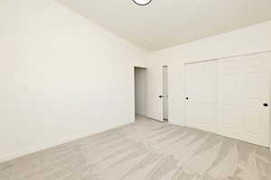 Unfurnished bedroom featuring carpet floors, a closet, and vaulted ceiling