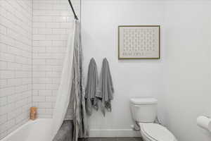 Bathroom featuring shower / bath combination with curtain and toilet