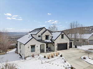 View of front of property featuring stone siding, covered porch, and driveway