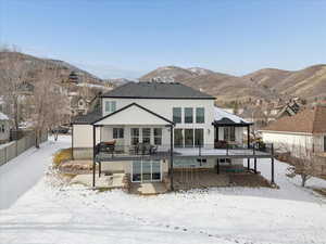 Snow covered house with a patio area, stucco siding, and a mountain view