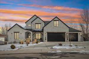 View of front of house with covered porch, driveway, and stone siding