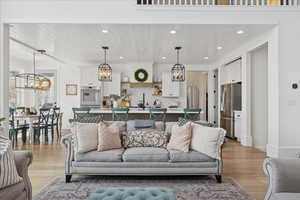 Living room with a chandelier, light wood-style floors, wood ceiling, arched walkways, and recessed lighting
