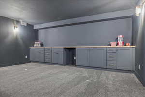 Bar area with gray cabinetry, dark colored carpet, a textured ceiling, and light countertops