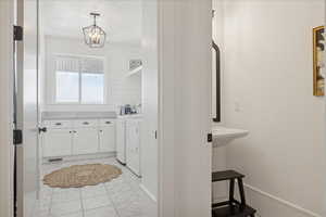 Bathroom with washer and clothes dryer, vanity, and light tile patterned floors